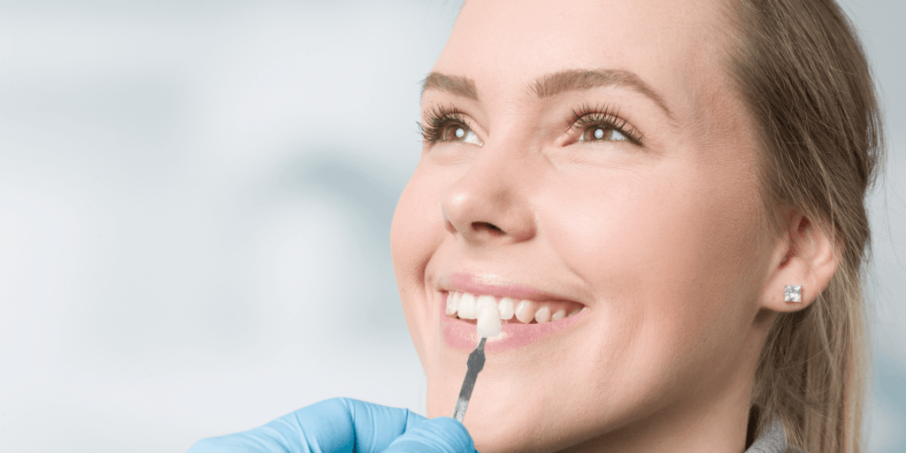 Dentist holding a tooth shade guide to match veneer color for a patient